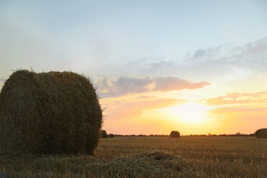 Beautiful view of agricultural field with hay bale at sunset