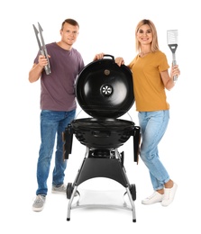 Happy couple with barbecue grill and utensils on white background