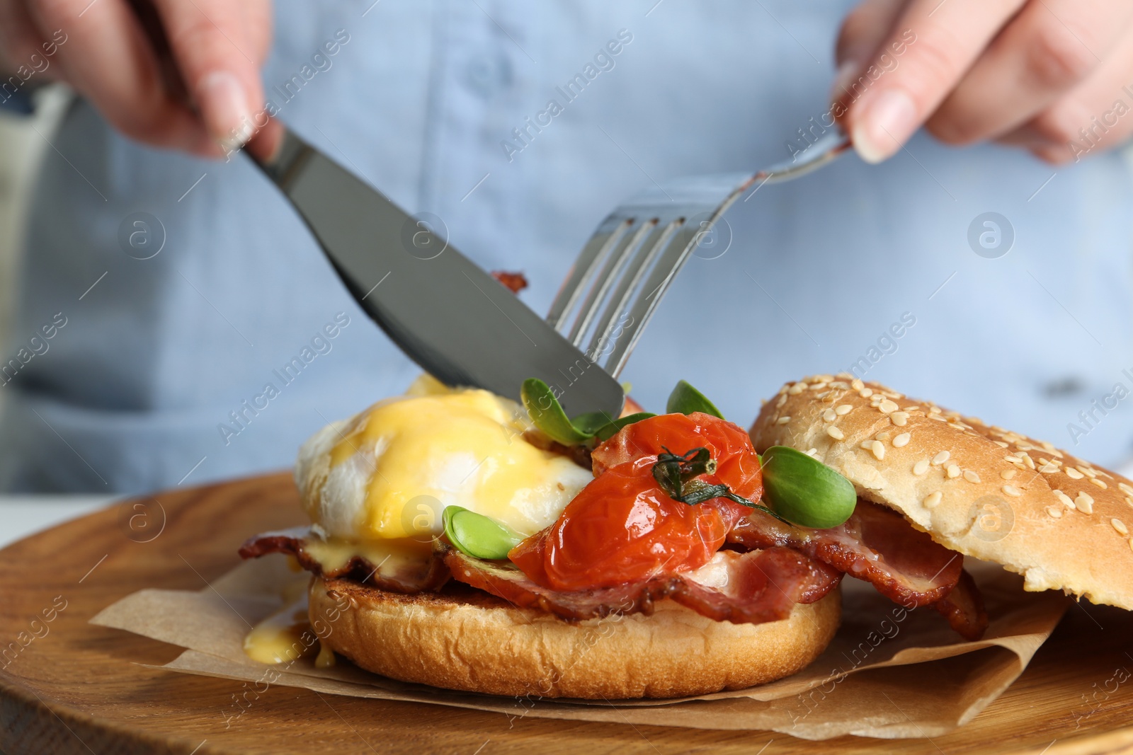 Photo of Woman eating tasty egg Benedict at table, closeup