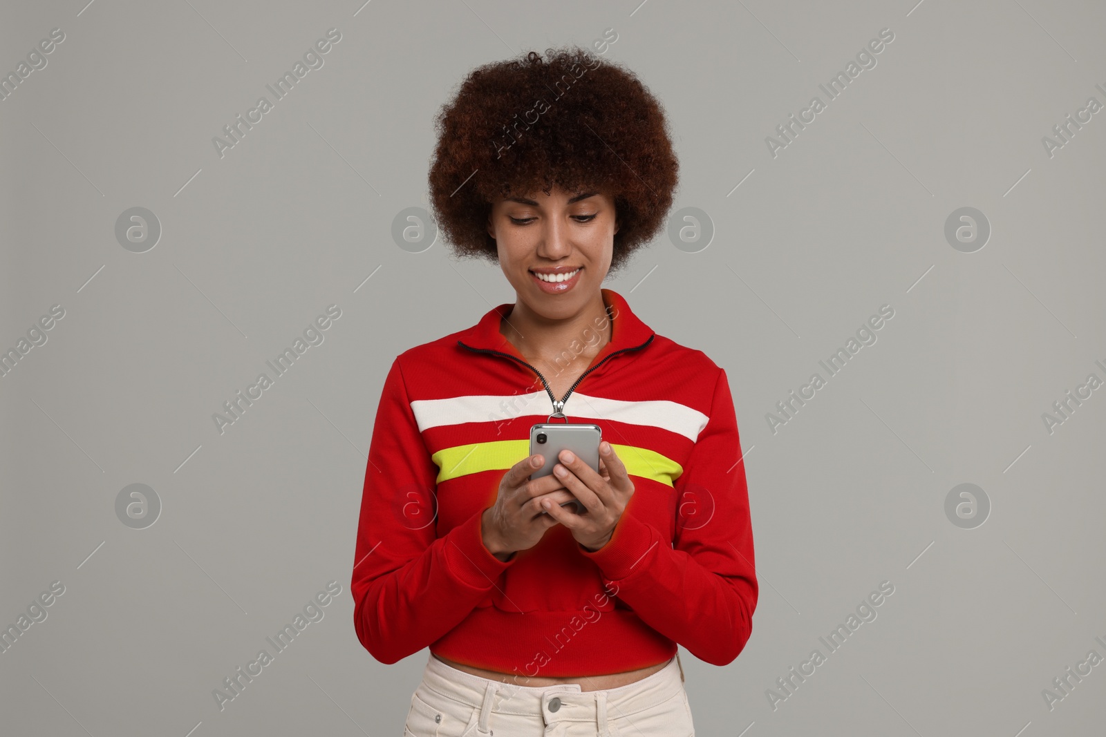 Photo of Happy young woman with smartphone on grey background