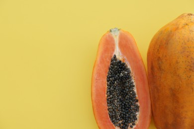 Photo of Fresh ripe cut and whole papaya fruits on light green background, flat lay. Space for text