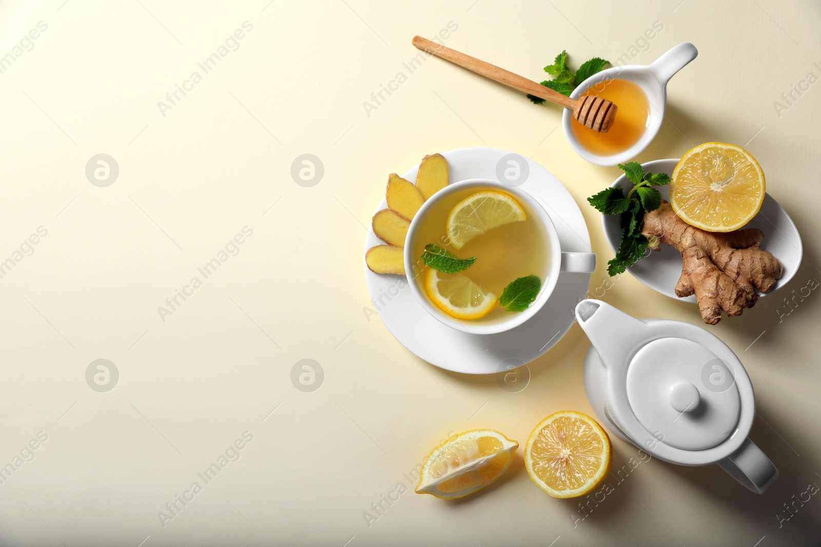 Photo of Delicious ginger tea and ingredients on beige background, flat lay. Space for text