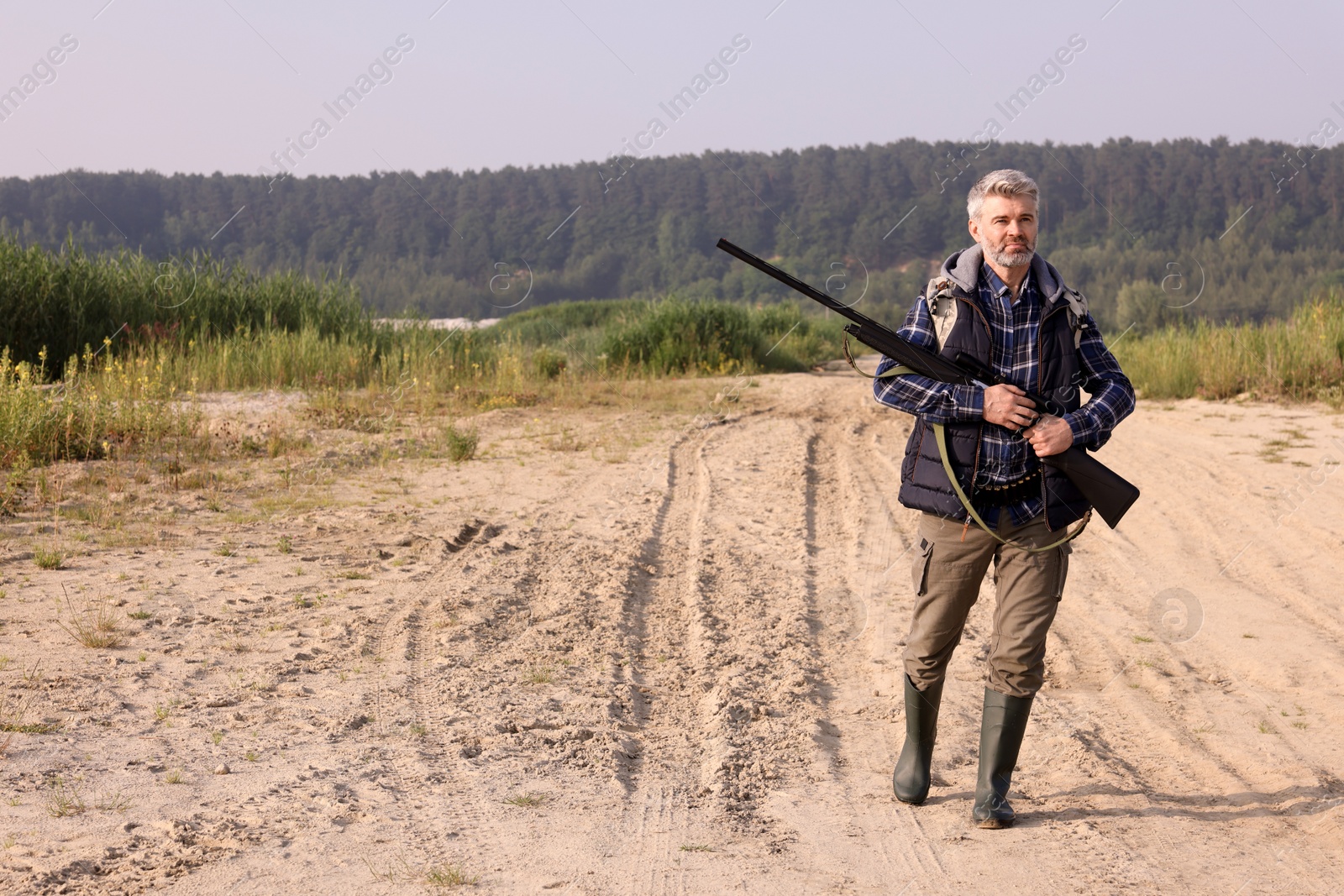 Photo of Man with hunting rifle outdoors. Space for text