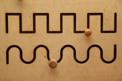 Photo of Wooden sliding maze with different lines as background, closeup. Montessori toy
