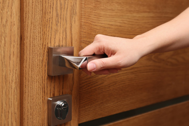 Photo of Woman opening wooden door indoors, closeup view