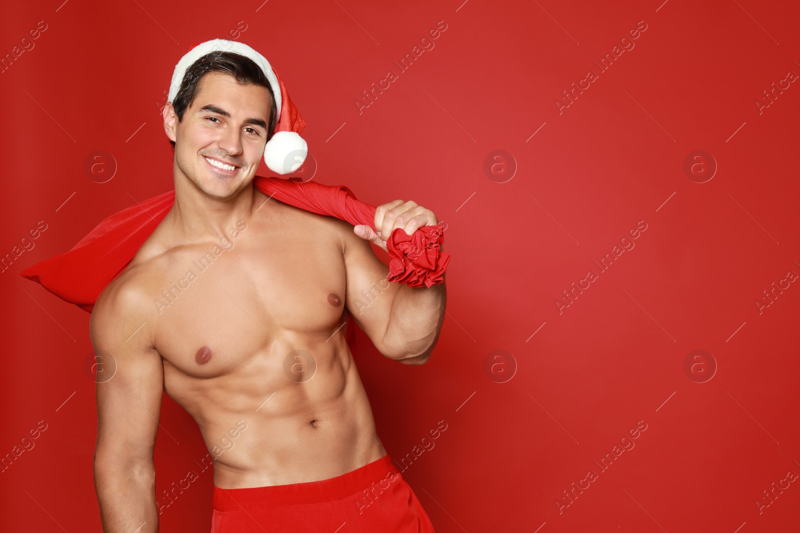 Photo of Sexy shirtless Santa Claus on red background, space for text