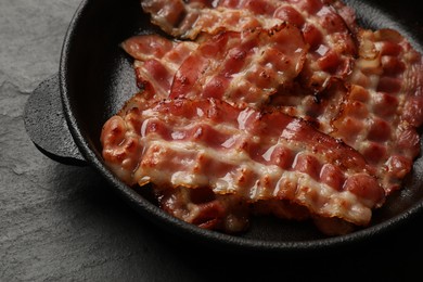 Photo of Fried bacon slices on dark textured table, closeup