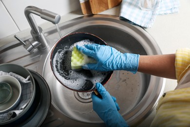 Photo of Woman washing dirty frying pan in sink, above view