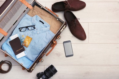 Packed suitcase on wooden background, top view. Space for text