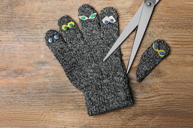 Photo of Divorce concept. Knitted glove and scissors on wooden table, flat lay