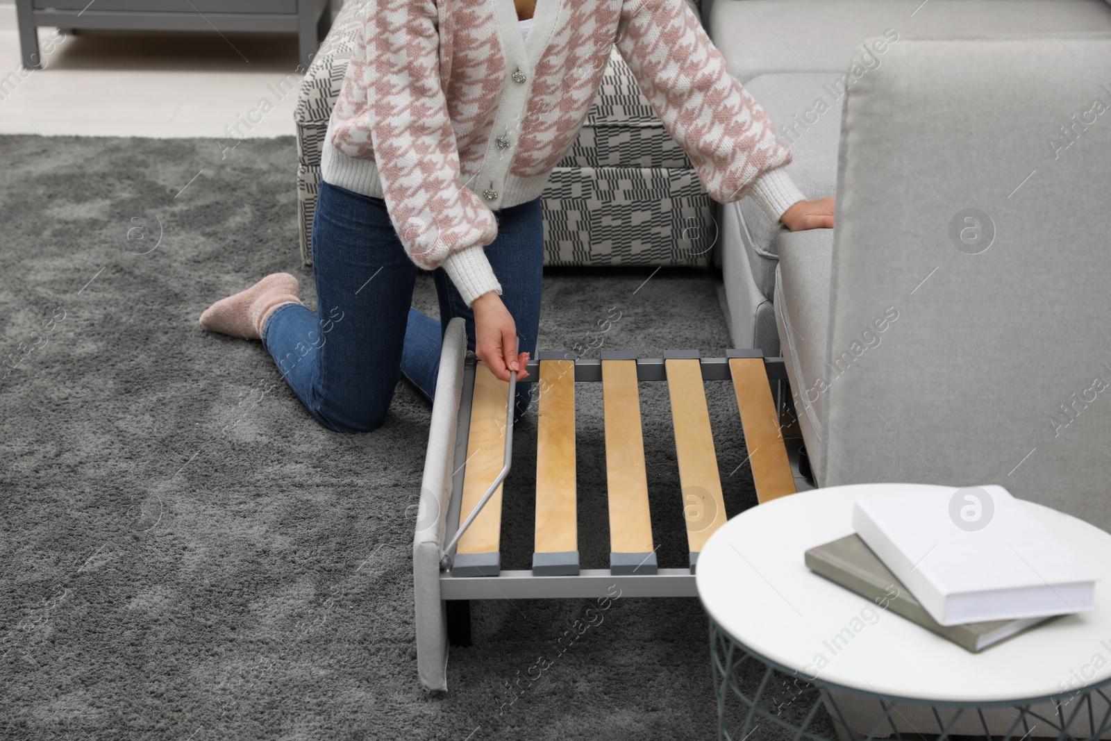 Photo of Woman making sleeping place for guest in living room, closeup. Convertible sofa