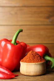 Photo of Paprika powder and fresh peppers on wooden table. Space for text