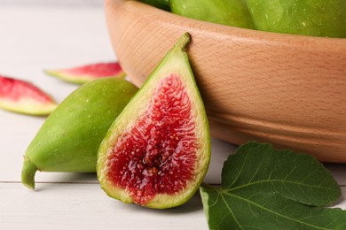 Cut and whole fresh green figs on white wooden table, closeup