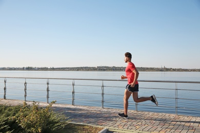 Sporty man running outdoors on sunny morning