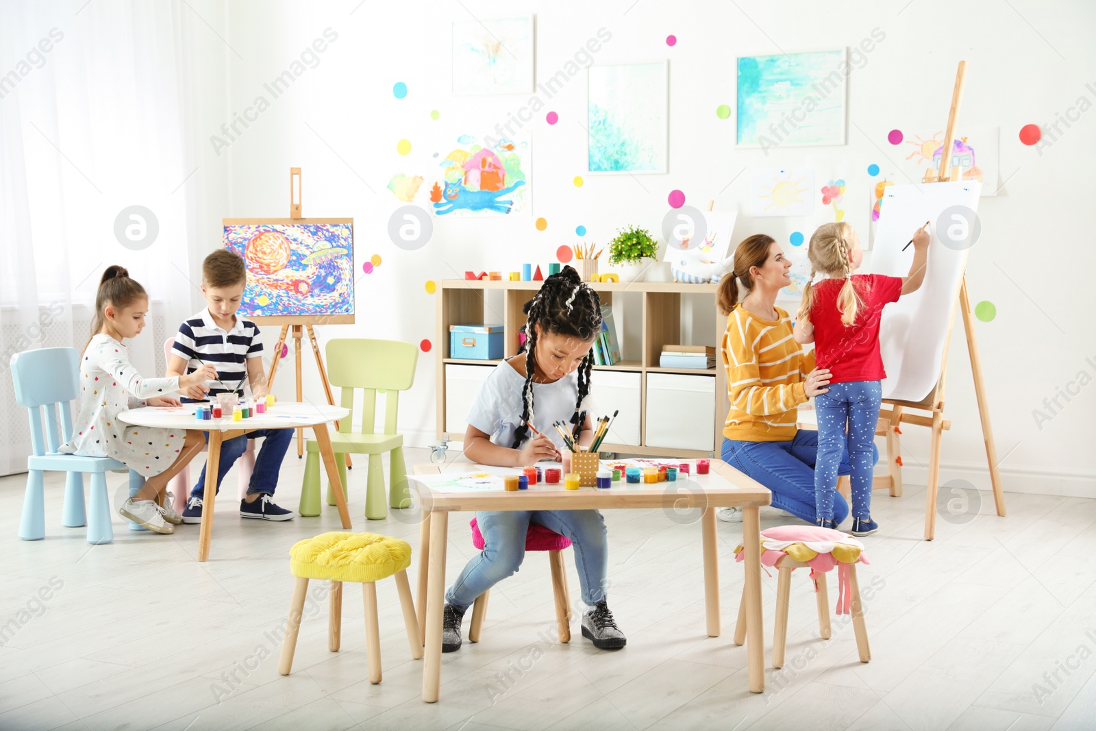 Photo of Children with female teacher at painting lesson indoors