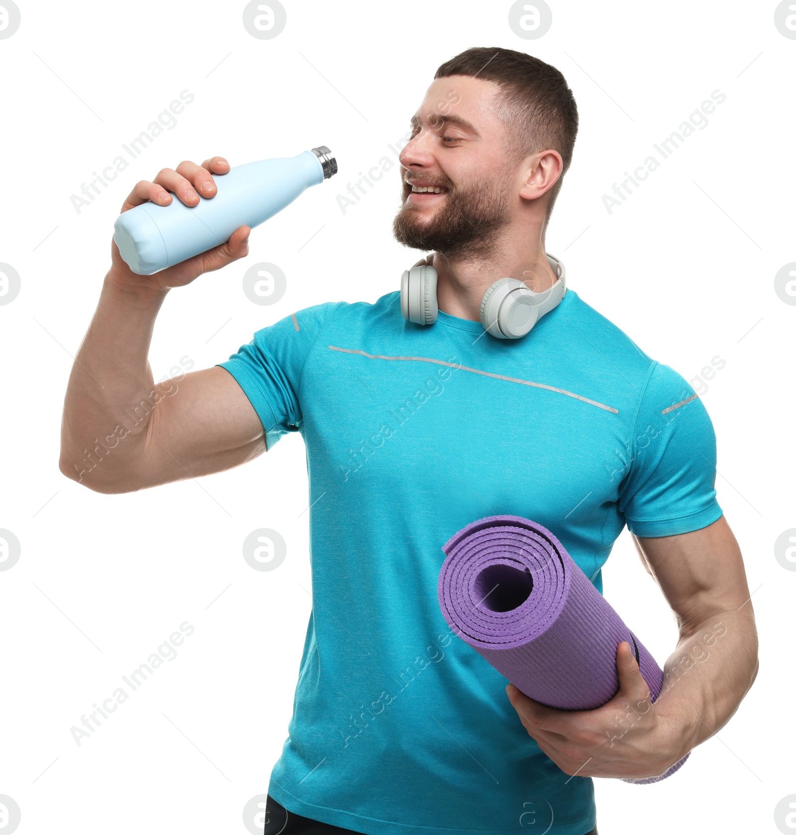 Photo of Handsome man with thermo bottle, fitness mat and headphones on white background