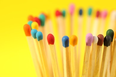 Photo of Matches with colorful heads on yellow background, closeup