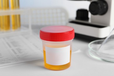 Photo of Container with urine sample for analysis on white table in laboratory