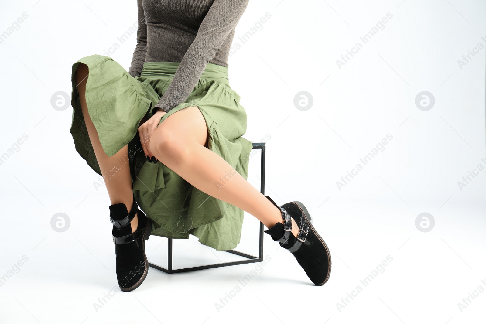 Photo of Woman in elegant shoes sitting on stool, white background