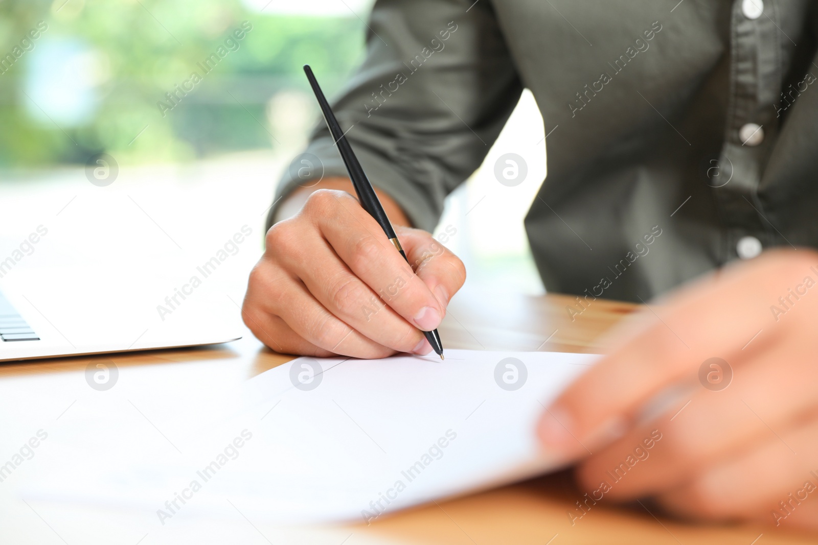 Photo of Male notary signing document at table in office, closeup