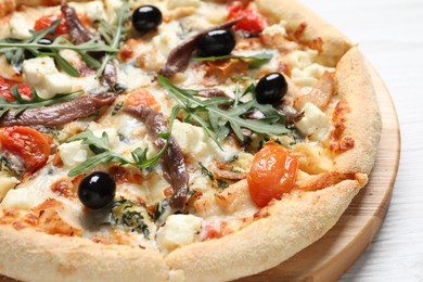 Tasty pizza with anchovies, arugula and olives on white wooden table, closeup