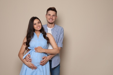 Pregnant woman and her husband on color background. Space for text