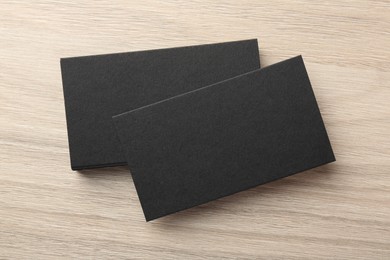 Photo of Blank black business cards on wooden table, top view. Mockup for design