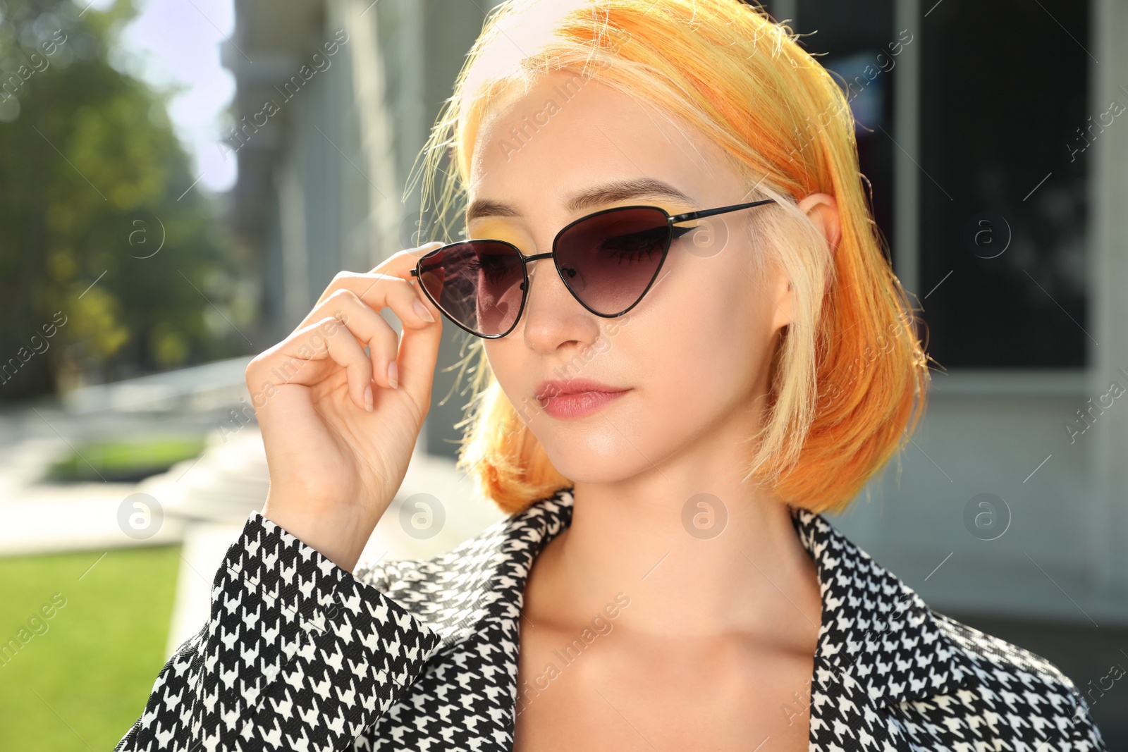 Photo of Beautiful young woman with bright dyed hair in sunglasses outdoors