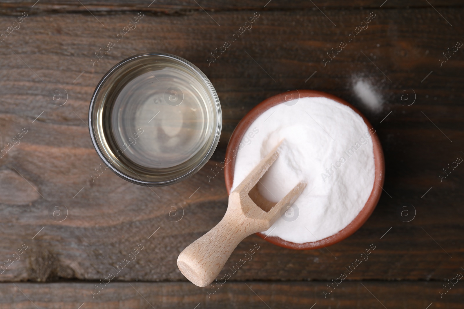 Photo of Vinegar in glass and baking soda on wooden table, top view