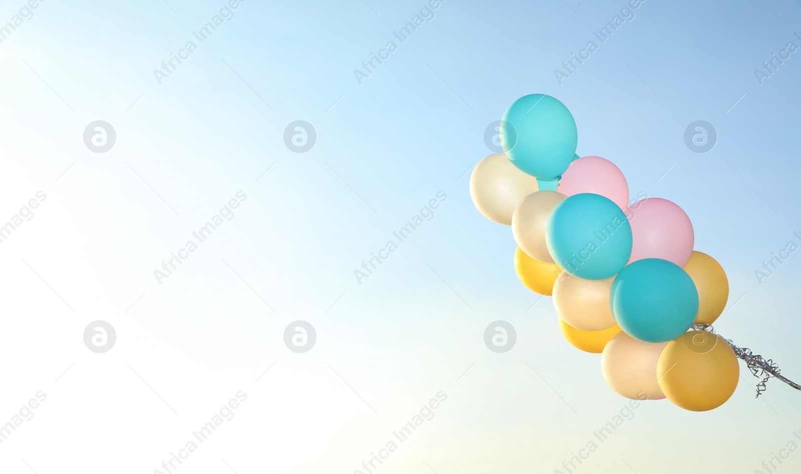 Photo of Bunch of colorful balloons against clear blue sky. Space for text