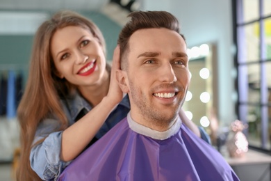 Professional hairdresser working with client in beauty salon