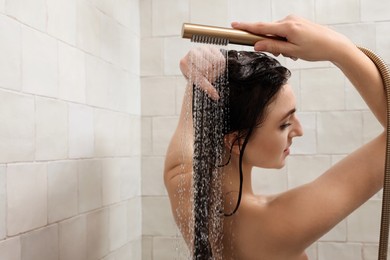 Photo of Young woman washing hair while taking shower at home, space for text