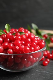 Photo of Fresh cranberry in bowl on dark grey table, closeup