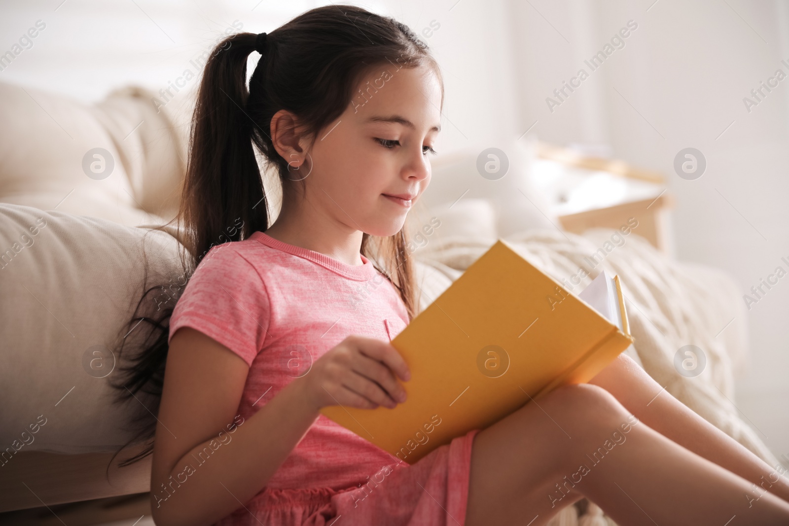 Photo of Little girl reading fairy tale in living room