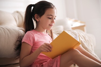 Little girl reading fairy tale in living room