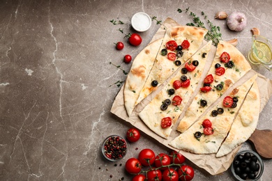 Photo of Delicious focaccia bread with olives and tomatoes on marble table, flat lay. Space for text