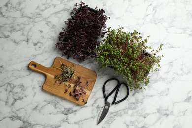 Fresh radish microgreens, wooden board and scissors on white marble table, flat lay