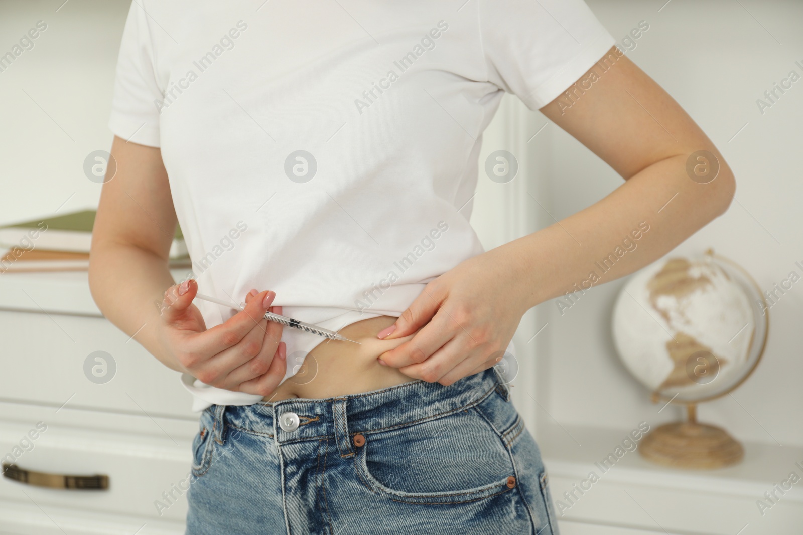 Photo of Diabetes. Woman making insulin injection into her belly indoors, closeup