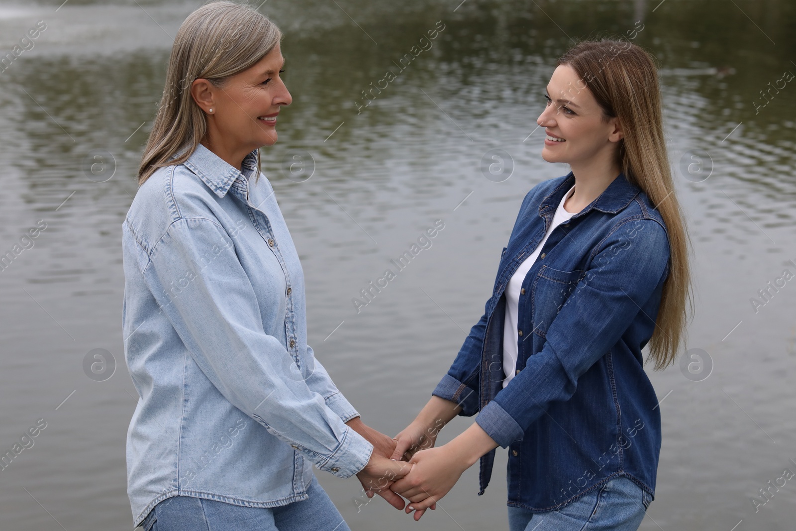 Photo of Happy mature mother and her daughter near pond