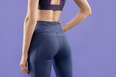 Woman wearing sportswear on violet background, back view
