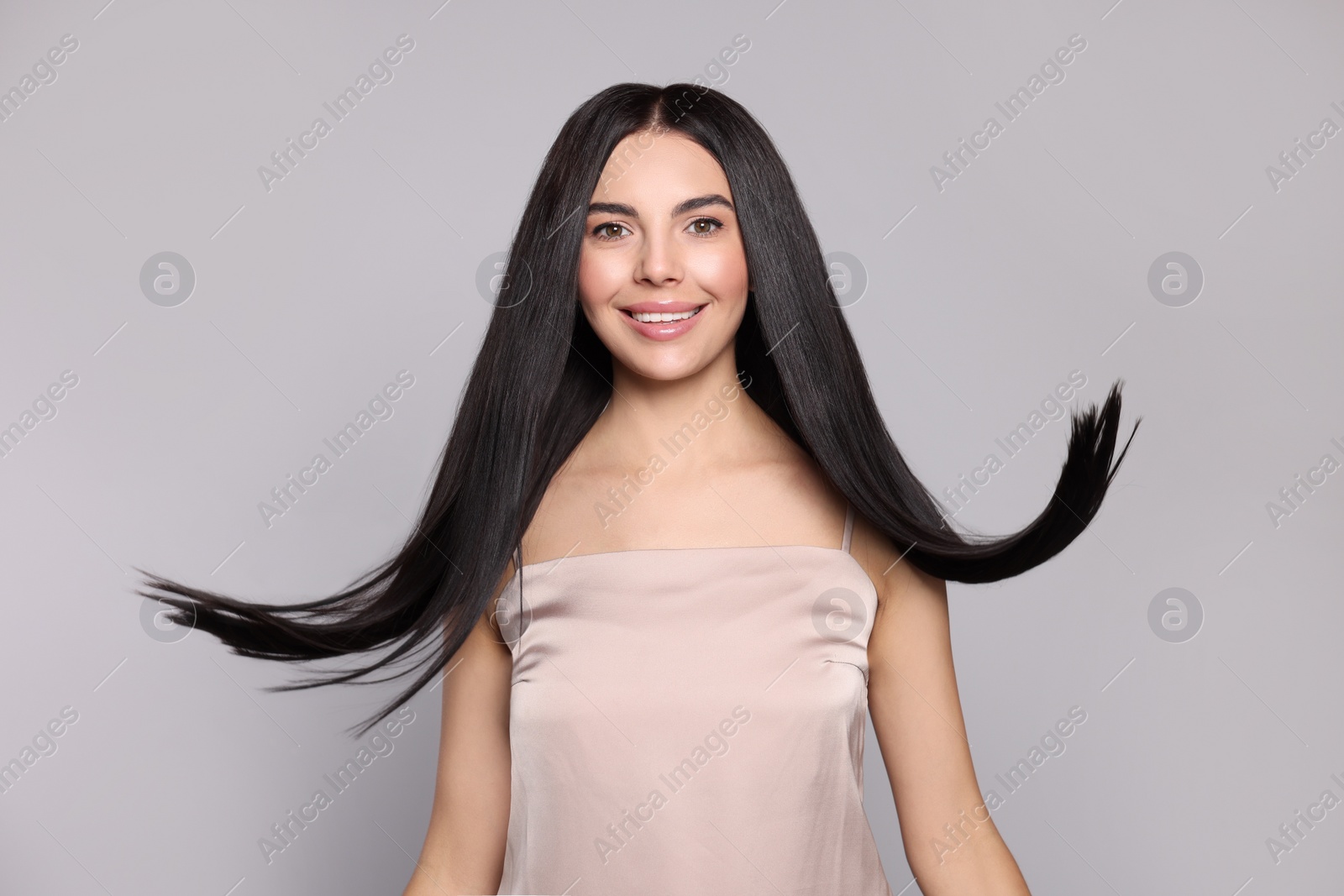 Photo of Portrait of beautiful young woman with healthy strong hair on light grey background