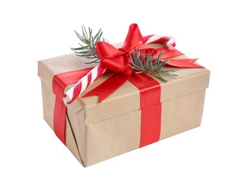 Christmas gift box decorated with red bow, candy cane and fir tree branch on white background