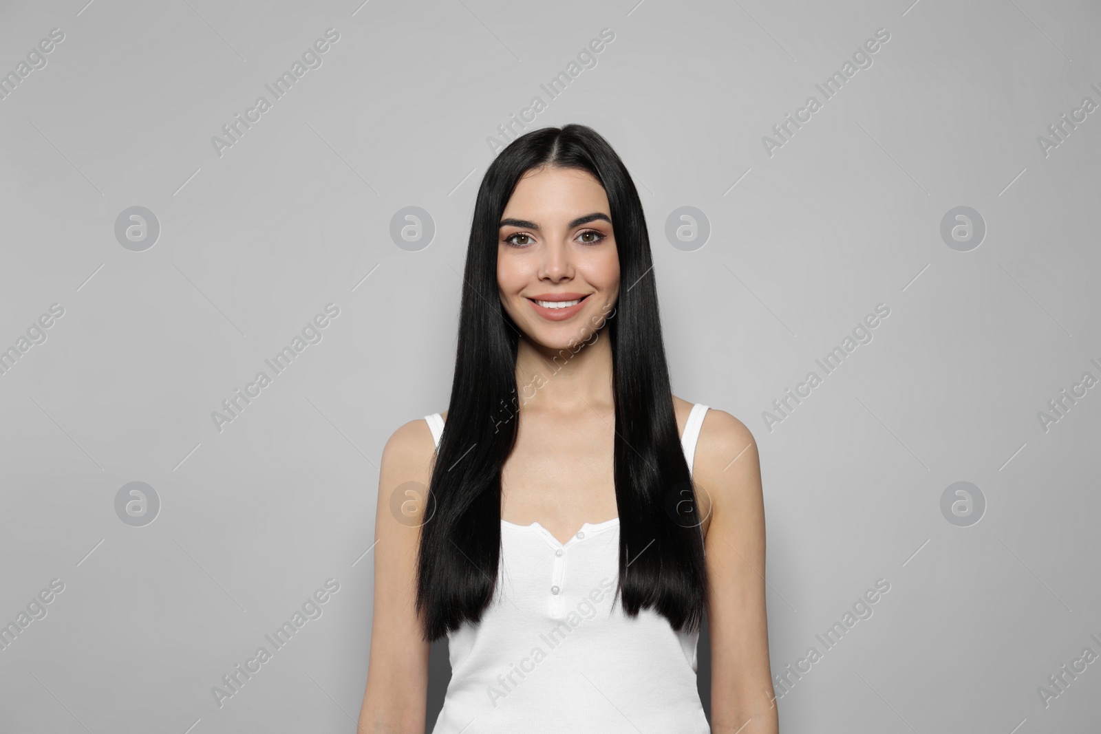 Photo of Beautiful young woman with long straight hair on grey background