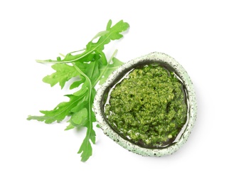 Photo of Bowl of tasty pesto and arugula on white background, top view