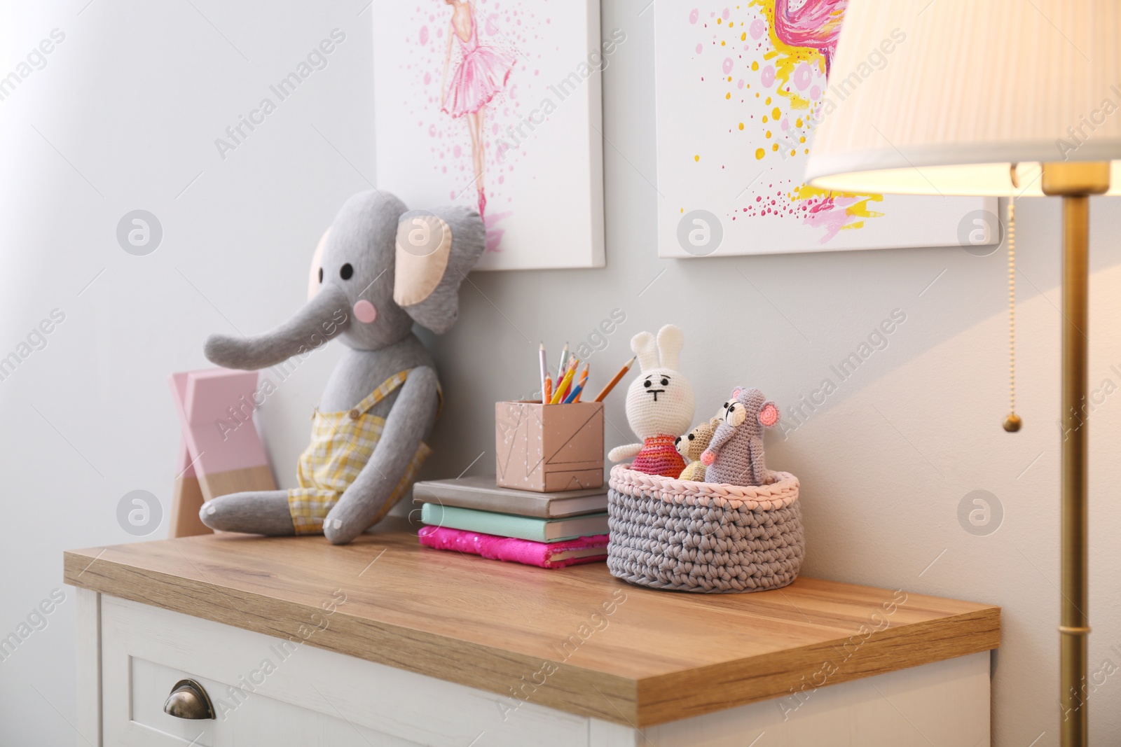 Photo of Chest of drawers and beautiful pictures in children's room. Interior design