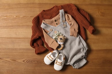 Photo of Children's shoes, clothes and toy on wooden table, flat lay