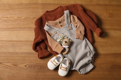 Children's shoes, clothes and toy on wooden table, flat lay