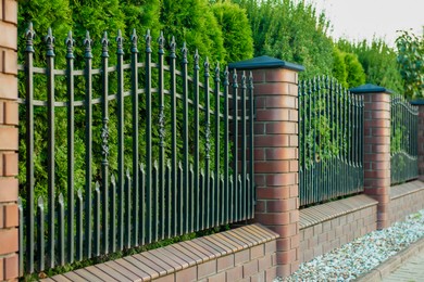 Photo of Beautiful brick fence with iron railing outdoors