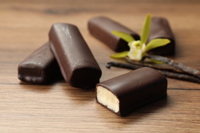 Glazed curd cheese bars, vanilla pods and flower on wooden table, closeup