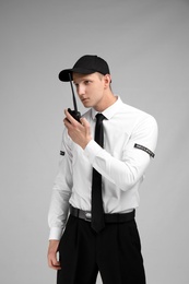 Male security guard using portable radio transmitter on color background